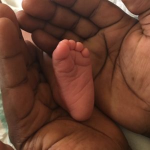 Hands cupping a newborn baby's foot